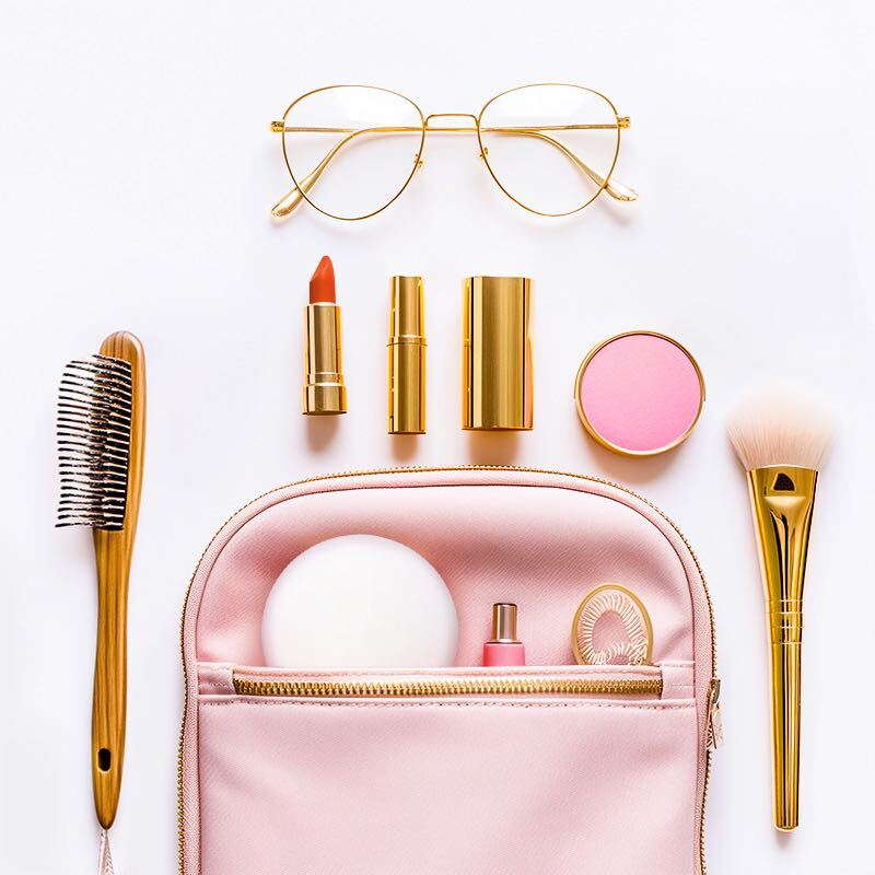 a pink bag with makeup brushes and lipsticks